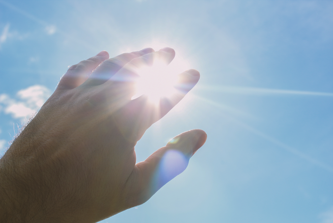 Une main placée devant le soleil